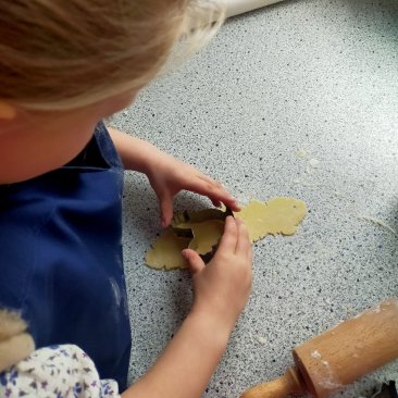 Kind is bezig met het maken van een koekje met een vormpje tijdens de graanles