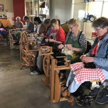 Wolwerkers druk aan het spinnen met de net geschoren schapenwol
