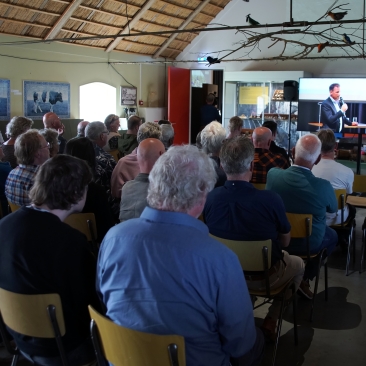 Mensen volgen de livestream van het debat in de foyer van het museum