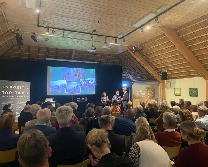 Familie Holtrop en H. van der Zwaag tijdens het startsymposium in een volle zaal